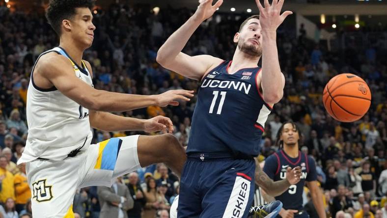 Marquette's Oso Ighodaro (13) swats the ball away from UConn forward Alex Karaban (11) during the second half of their game Wednesday, March 6, 2024 at Fiserv Forum in Milwaukee, Wisconsin. UConn beat Marquette 74-67.