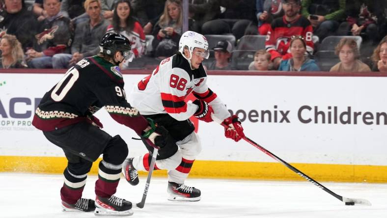 Mar 16, 2024; Tempe, Arizona, USA; New Jersey Devils center Jack Hughes (86) skates against Arizona Coyotes defenseman J.J. Moser (90) during the third period at Mullett Arena. Mandatory Credit: Joe Camporeale-USA TODAY Sports