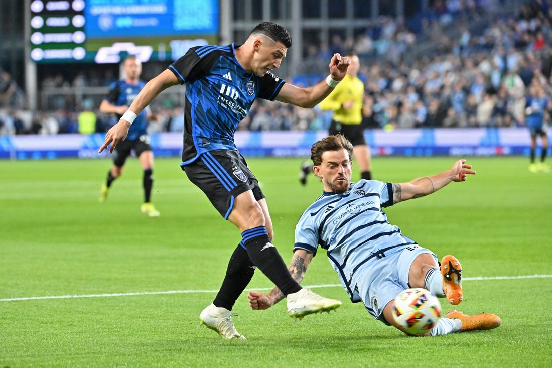 Mar 16, 2024; Kansas City, Kansas, USA; San Jose Earthquakes midfielder Cristian Espinoza (10) shoots the ball against Sporting Kansas City defender Tim Leibold (14) during the first half  at Children's Mercy Park. Mandatory Credit: Peter Aiken-USA TODAY Sports