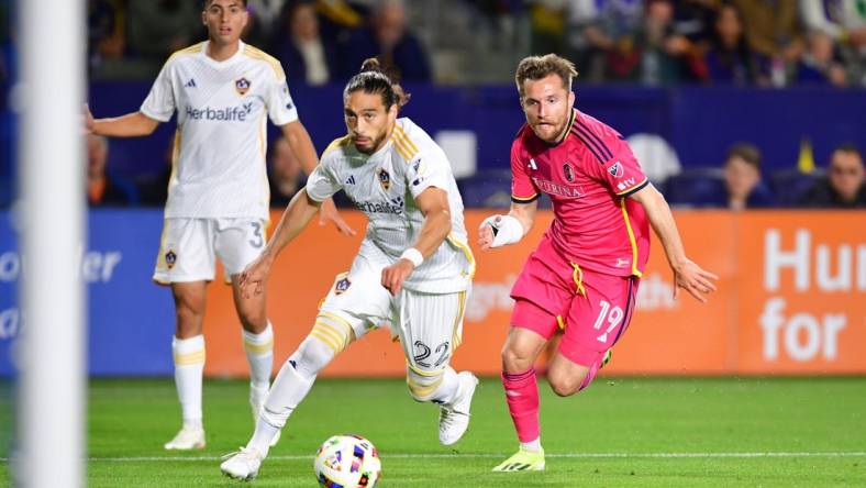 Mar 16, 2024; Carson, California, USA; LA Galaxy defender Martin Caceres (22) and St. Louis CITY SC midfielder Indiana Vassilev (19) chase down the ball during the first half at Dignity Health Sports Park. Mandatory Credit: Gary A. Vasquez-USA TODAY Sports