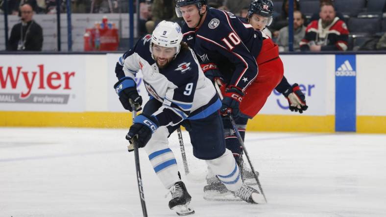 Mar 17, 2024; Columbus, Ohio, USA; Winnipeg Jets left wing Alex Iafallo (9) passes the puck as Columbus Blue Jackets left wing Dmitri Voronkov (10) trails the play during the first period at Nationwide Arena. Mandatory Credit: Russell LaBounty-USA TODAY Sports