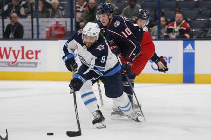 Mar 17, 2024; Columbus, Ohio, USA; Winnipeg Jets left wing Alex Iafallo (9) passes the puck as Columbus Blue Jackets left wing Dmitri Voronkov (10) trails the play during the first period at Nationwide Arena. Mandatory Credit: Russell LaBounty-USA TODAY Sports