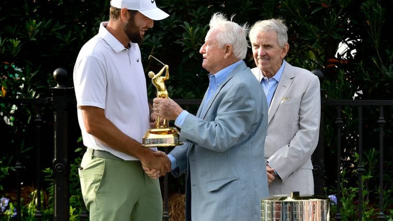 Deane Beman, the PGA Tour Commissioner to oversee the first Players Championship presents Scottie Scheffler his Gold Man tournament trophy as former Commissioner Tim Finchem looks on during the trophy ceremony following the fourth and final round of The Players Championship PGA golf tournament Sunday, March 17, 2024 at TPC Sawgrass in Ponte Vedra Beach, Fla. [Bob Self/Florida Times-Union]