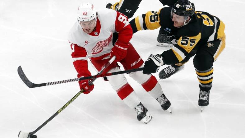 Mar 17, 2024; Pittsburgh, Pennsylvania, USA;  Detroit Red Wings right wing Alex DeBrincat (93) skates with he puck against Pittsburgh Penguins center Noel Acciari (55) during the third period at PPG Paints Arena. Pittsburgh won 6-3. Mandatory Credit: Charles LeClaire-USA TODAY Sports