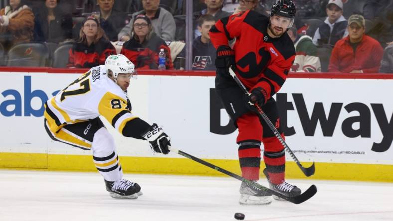 Mar 19, 2024; Newark, New Jersey, USA; New Jersey Devils defenseman Brendan Smith (2) passes the puck while being defended by Pittsburgh Penguins center Sidney Crosby (87) during the first period at Prudential Center. Mandatory Credit: Ed Mulholland-USA TODAY Sports