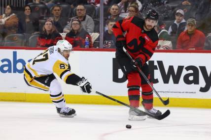 Mar 19, 2024; Newark, New Jersey, USA; New Jersey Devils defenseman Brendan Smith (2) passes the puck while being defended by Pittsburgh Penguins center Sidney Crosby (87) during the first period at Prudential Center. Mandatory Credit: Ed Mulholland-USA TODAY Sports
