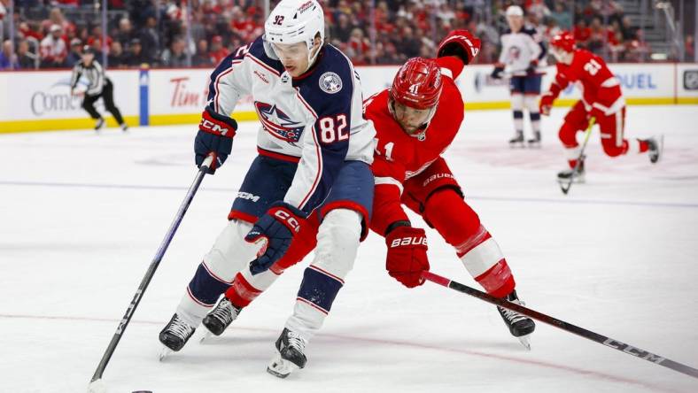 Mar 19, 2024; Detroit, Michigan, USA; Columbus Blue Jackets left wing Mikael Pyyhtia (82) handles the puck against Detroit Red Wings defenseman Shayne Gostisbehere (41) during the first period of the game against the Detroit Red Wings at Little Caesars Arena. Mandatory Credit: Brian Bradshaw Sevald-USA TODAY Sports