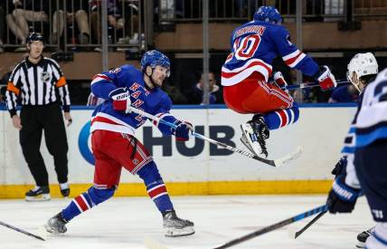 Mar 19, 2024; New York, New York, USA; New York Rangers left wing Artemi Panarin (10) jumps over a shot by New York Rangers forward Alexis Lafreniere (13) during the third period against the Winnipeg Jets at Madison Square Garden. Mandatory Credit: Danny Wild-USA TODAY Sports