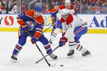 Mar 16, 2024; Edmonton, Alberta, CAN; Edmonton Oilers forward Connor McDavid (97) tries to carry the puck around Montreal Canadiens defensemen Kaiden Guhle (21) during the first period at Rogers Place. Mandatory Credit: Perry Nelson-USA TODAY Sports