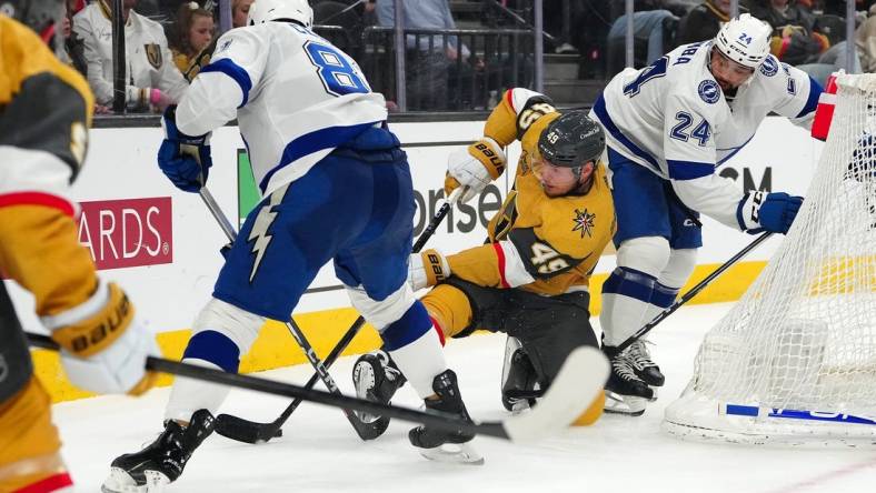 Mar 19, 2024; Las Vegas, Nevada, USA; Vegas Golden Knights center Ivan Barbashev (49) attempts to control the puck between Tampa Bay Lightning defenseman Erik Cernak (81) and Tampa Bay Lightning defenseman Matt Dumba (24) during the second period at T-Mobile Arena. Mandatory Credit: Stephen R. Sylvanie-USA TODAY Sports