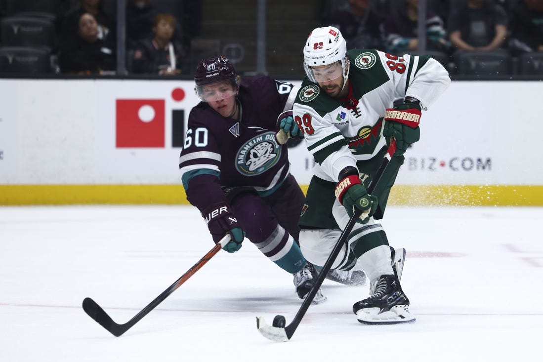 Mar 19, 2024; Anaheim, California, USA; Minnesota Wild center Frederick Gaudreau (89) skates with the puck against Anaheim Ducks defenseman Jackson LaCombe (60) during the third period of a game at Honda Center. Mandatory Credit: Jessica Alcheh-USA TODAY Sports