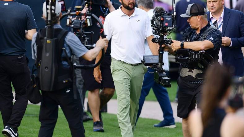 Scottie Scheffler is surrounded by cameras as he makes his way to the trophy riser after winning the tournament for the second year in a row at The Players Championship PGA golf tournament Sunday, March 17, 2024 at TPC Sawgrass in Ponte Vedra Beach, Fla.