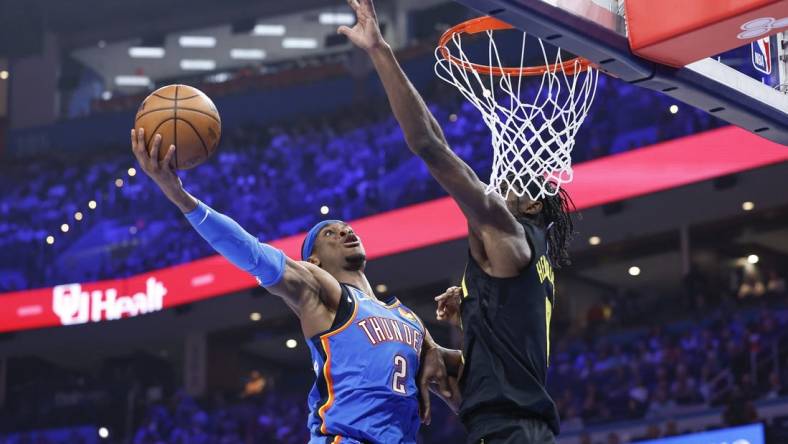 Mar 20, 2024; Oklahoma City, Oklahoma, USA; Oklahoma City Thunder guard Shai Gilgeous-Alexander (2) goes to the basket as Utah Jazz forward Taylor Hendricks (0) defends during the second quarter at Paycom Center. Mandatory Credit: Alonzo Adams-USA TODAY Sports