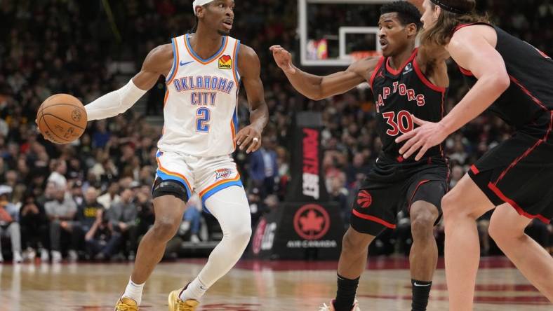 Mar 22, 2024; Toronto, Ontario, CAN; Oklahoma City Thunder guard Shai Gilgeous-Alexander (2) looks to make a play against Toronto Raptors guard Ochai Agbaji (30) and  forward Kelly Olynyk (41) during the first half at Scotiabank Arena. Mandatory Credit: John E. Sokolowski-USA TODAY Sports