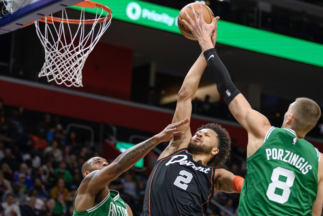 Mar 22, 2024; Detroit, Michigan, USA; Detroit Pistons guard Cade Cunningham (2) gets fouled while driving to the basket against  Boston Celtics forward Xavier Tillman (26) and  center Kristaps Porzingis (8) in the first quarter at Little Caesars Arena. Mandatory Credit: Lon Horwedel-USA TODAY Sports