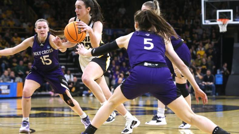 Iowa’s Caitlin Clark (22) dribbles between a host of Holy Cross defenders in a first-round NCAA Tournament game Saturday, March 23, 2024 at Carver-Hawkeye Arena in Iowa City, Iowa.