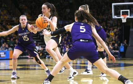 Iowa’s Caitlin Clark (22) dribbles between a host of Holy Cross defenders in a first-round NCAA Tournament game Saturday, March 23, 2024 at Carver-Hawkeye Arena in Iowa City, Iowa.