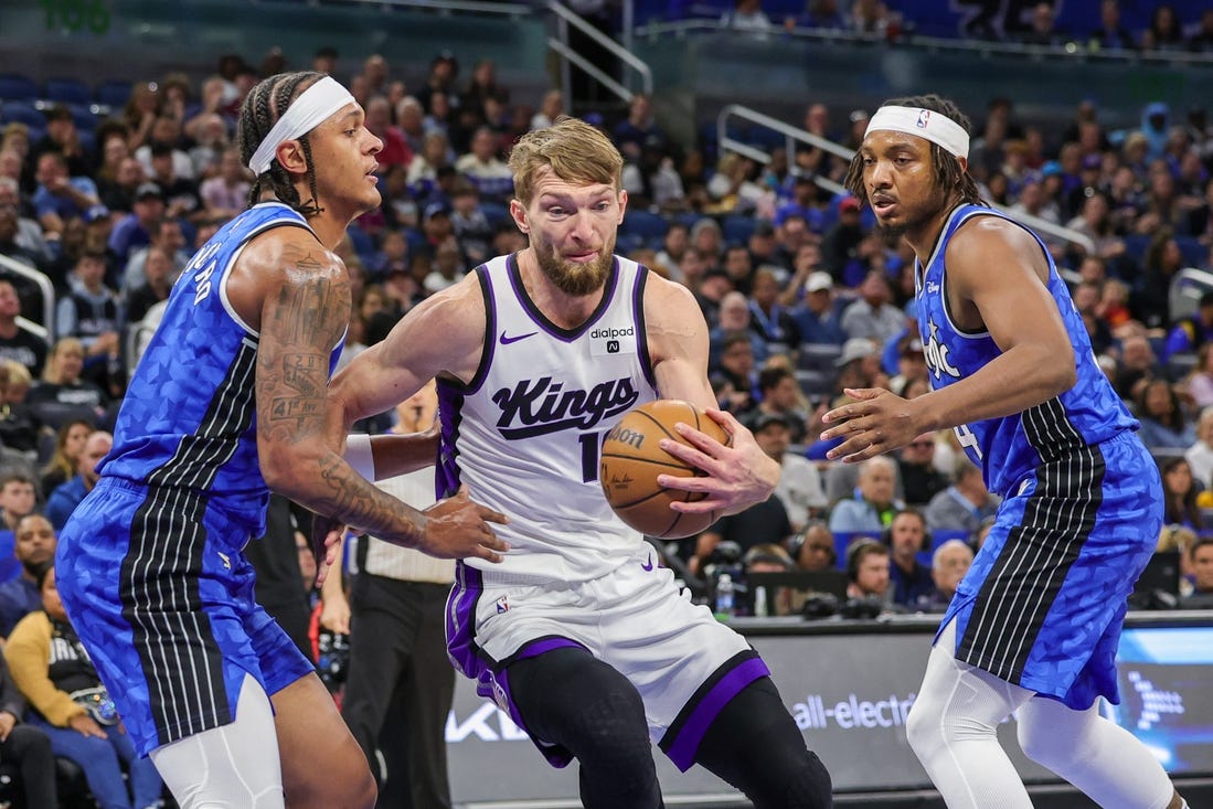 Mar 23, 2024; Orlando, Florida, USA; Sacramento Kings forward Domantas Sabonis (10) drives to the basket against Orlando Magic forward Paolo Banchero (5) and Orlando Magic center Wendell Carter Jr. (34) during the first quarter at KIA Center. Mandatory Credit: Mike Watters-USA TODAY Sports