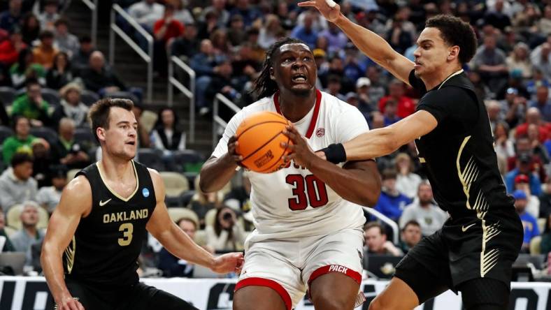 Mar 23, 2024; Pittsburgh, PA, USA; North Carolina State Wolfpack forward DJ Burns Jr. (30) drives to the basket against Oakland Golden Grizzlies forward Chris Conway (2) and guard Jack Gohlke (3) during the second half in the second round of the 2024 NCAA Tournament at PPG Paints Arena. Mandatory Credit: Charles LeClaire-USA TODAY Sports