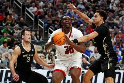 Mar 23, 2024; Pittsburgh, PA, USA; North Carolina State Wolfpack forward DJ Burns Jr. (30) drives to the basket against Oakland Golden Grizzlies forward Chris Conway (2) and guard Jack Gohlke (3) during the second half in the second round of the 2024 NCAA Tournament at PPG Paints Arena. Mandatory Credit: Charles LeClaire-USA TODAY Sports