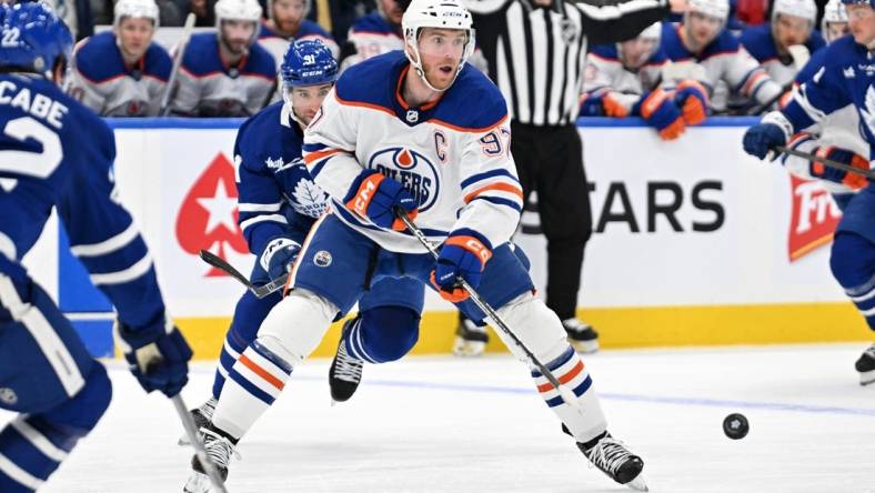 Mar 23, 2024; Toronto, Ontario, CAN; Edmonton Oilers forward Connor McDavid (97) passes the puck against the Toronto Maple Leafs in the second period at Scotiabank Arena. Mandatory Credit: Dan Hamilton-USA TODAY Sports