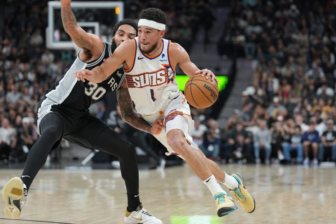 Mar 23, 2024; San Antonio, Texas, USA;  Phoenix Suns guard Devin Booker (1) dribbles against San Antonio Spurs forward Julian Champagnie (30) in the second half at Frost Bank Center. Mandatory Credit: Daniel Dunn-USA TODAY Sports