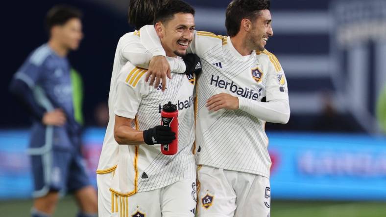 Mar 23, 2024; Kansas City, Kansas, USA; LA Galaxy midfielder Mark Delgado (8) and midfielder Gaston Brugman (5) celebrate after a Galaxy goal against Sporting Kansas City during the second half at Children's Mercy Park. Mandatory Credit: William Purnell-USA TODAY Sports