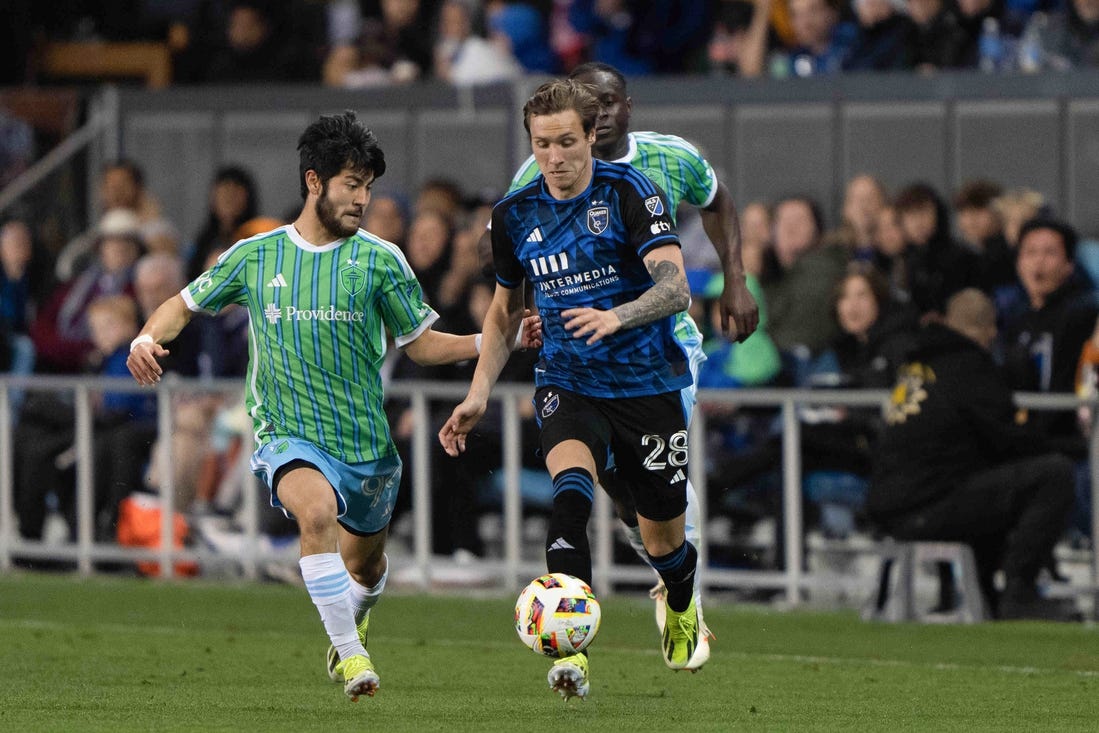 Mar 23, 2024; San Jose, California, USA; San Jose Earthquakes forward Benji Kikanovic (28) dribbles the ball while Seattle Sounders FC midfielder Dylan Teves (99) defends during the second half at PayPal Park. Mandatory Credit: Stan Szeto-USA TODAY Sports