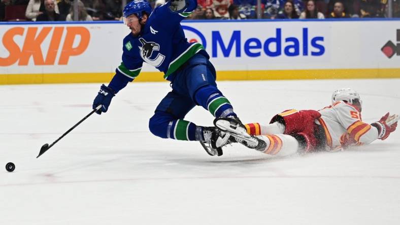 Mar 23, 2024; Vancouver, British Columbia, CAN; Vancouver Canucks forward J.T. Miller (9) checked by Calgary Flames defenseman Olivver Kylington (58) during the third period at Rogers Arena. Mandatory Credit: Simon Fearn-USA TODAY Sports