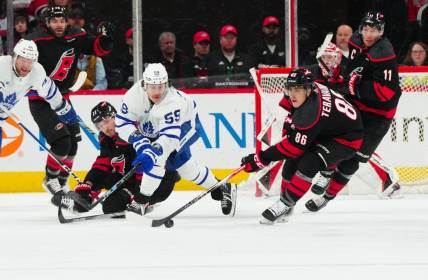Mar 24, 2024; Raleigh, North Carolina, USA;  Carolina Hurricanes defenseman Brett Pesce (22) and left wing Teuvo Teravainen (86) battle Toronto Maple Leafs left wing Tyler Bertuzzi (59) for the puck during the first period at PNC Arena. Mandatory Credit: James Guillory-USA TODAY Sports
