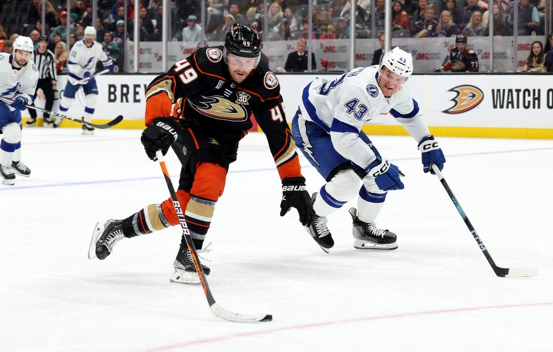 Mar 24, 2024; Anaheim, California, USA; Anaheim Ducks left wing Max Jones (49) keeps the puck from Tampa Bay Lightning defenseman Darren Raddysh (43) during the second period at Honda Center. Mandatory Credit: Jason Parkhurst-USA TODAY Sports