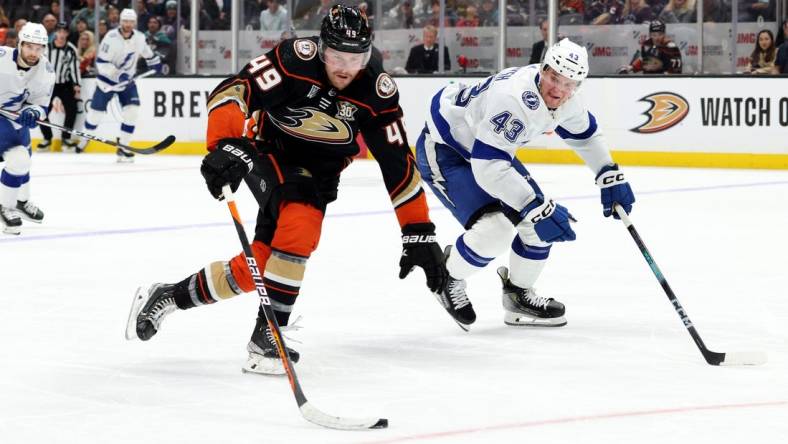 Mar 24, 2024; Anaheim, California, USA; Anaheim Ducks left wing Max Jones (49) keeps the puck from Tampa Bay Lightning defenseman Darren Raddysh (43) during the second period at Honda Center. Mandatory Credit: Jason Parkhurst-USA TODAY Sports