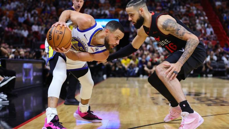 Mar 26, 2024; Miami, Florida, USA; Golden State Warriors guard Stephen Curry (30) protects the basketball from Miami Heat forward Caleb Martin (16) during the first quarter at Kaseya Center. Mandatory Credit: Sam Navarro-USA TODAY Sports