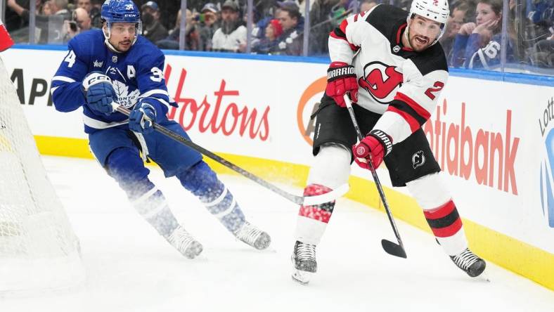 Mar 26, 2024; Toronto, Ontario, CAN; Toronto Maple Leafs center Auston Matthews (34) battles for the puck with New Jersey Devils defenseman Brendan Smith (2) during the first period at Scotiabank Arena. Mandatory Credit: Nick Turchiaro-USA TODAY Sports