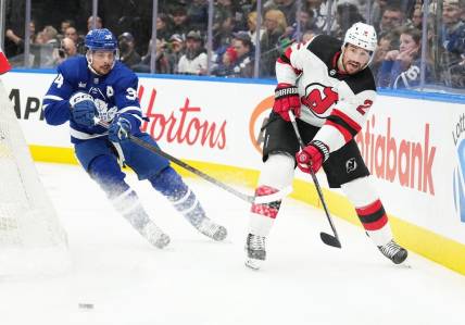 Mar 26, 2024; Toronto, Ontario, CAN; Toronto Maple Leafs center Auston Matthews (34) battles for the puck with New Jersey Devils defenseman Brendan Smith (2) during the first period at Scotiabank Arena. Mandatory Credit: Nick Turchiaro-USA TODAY Sports