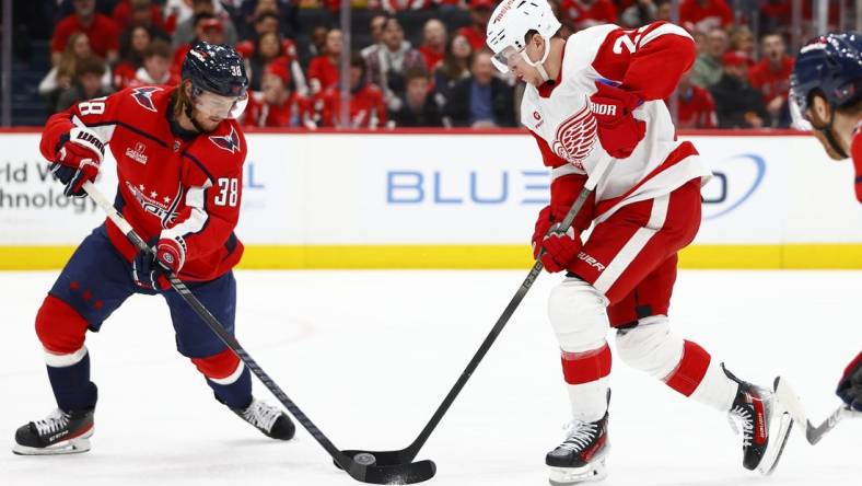 Mar 26, 2024; Washington, District of Columbia, USA; Detroit Red Wings left wing Lucas Raymond (23) battles for the puck with Washington Capitals defenseman Rasmus Sandin (38) during the second period at Capital One Arena. Mandatory Credit: Amber Searls-USA TODAY Sports