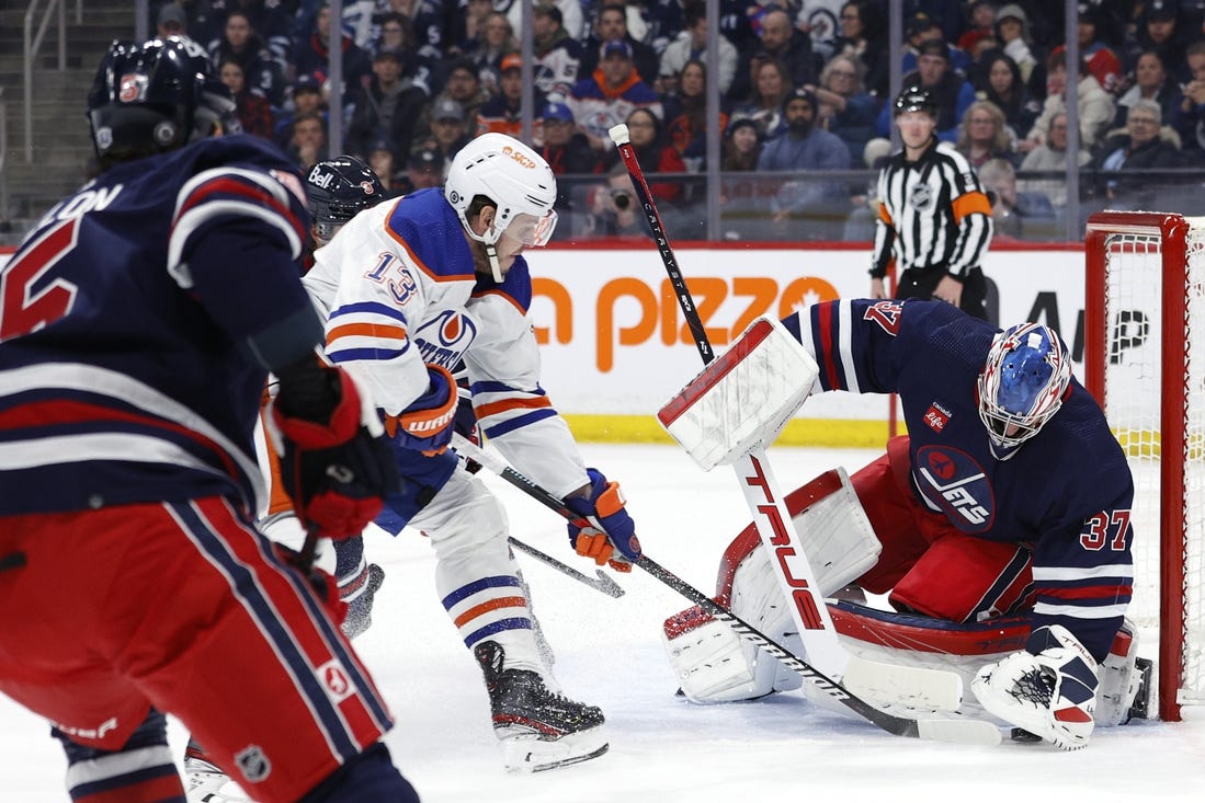 Mar 26, 2024; Winnipeg, Manitoba, CAN; Winnipeg Jets goaltender Connor Hellebuyck (37) covers up a rebound from Edmonton Oilers center Mattias Janmark (13) in the first period at Canada Life Centre. Mandatory Credit: James Carey Lauder-USA TODAY Sports