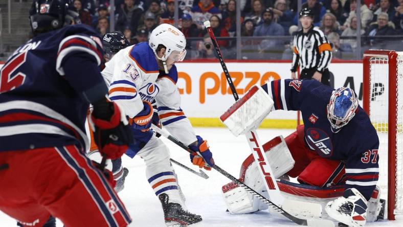 Mar 26, 2024; Winnipeg, Manitoba, CAN; Winnipeg Jets goaltender Connor Hellebuyck (37) covers up a rebound from Edmonton Oilers center Mattias Janmark (13) in the first period at Canada Life Centre. Mandatory Credit: James Carey Lauder-USA TODAY Sports