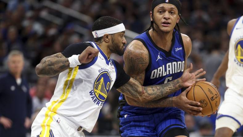 Mar 27, 2024; Orlando, Florida, USA;  Orlando Magic forward Paolo Banchero (5) drives the ball past Golden State Warriors guard Gary Payton II (0) in the second quarter at the Kia Center. Mandatory Credit: Nathan Ray Seebeck-USA TODAY Sports