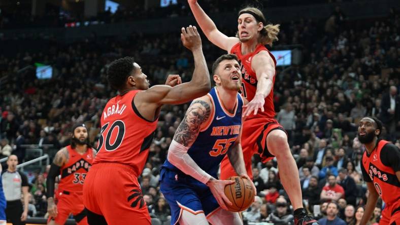 Mar 27, 2024; Toronto, Ontario, CAN; New York Knicks center Isaiah Hartenstein (55) drives against Toronto Raptors forward Kelly Olynyk (41) and guard Ochai Agbaji (30) in the first half at Scotiabank Arena. Mandatory Credit: Dan Hamilton-USA TODAY Sports