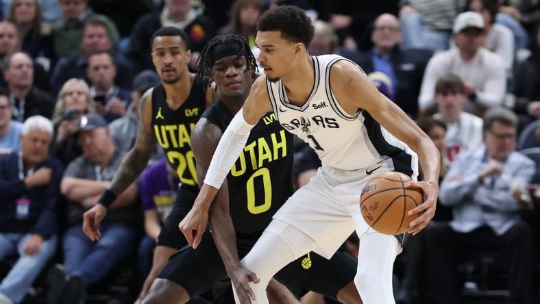 Mar 27, 2024; Salt Lake City, Utah, USA; San Antonio Spurs center Victor Wembanyama (1) moves the ball away from Utah Jazz forward Taylor Hendricks (0) during the second quarter at Delta Center. Mandatory Credit: Rob Gray-USA TODAY Sports