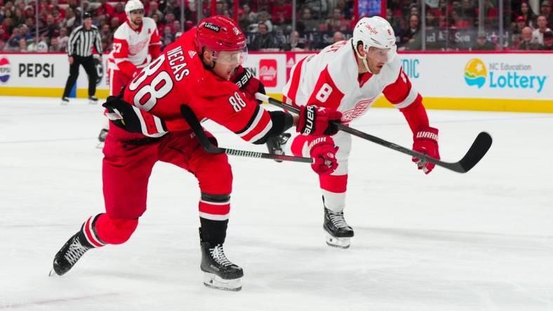 Mar 28, 2024; Raleigh, North Carolina, USA;  Carolina Hurricanes center Martin Necas (88) gets the shot past Detroit Red Wings defenseman Ben Chiarot (8) during the second period at PNC Arena. Mandatory Credit: James Guillory-USA TODAY Sports