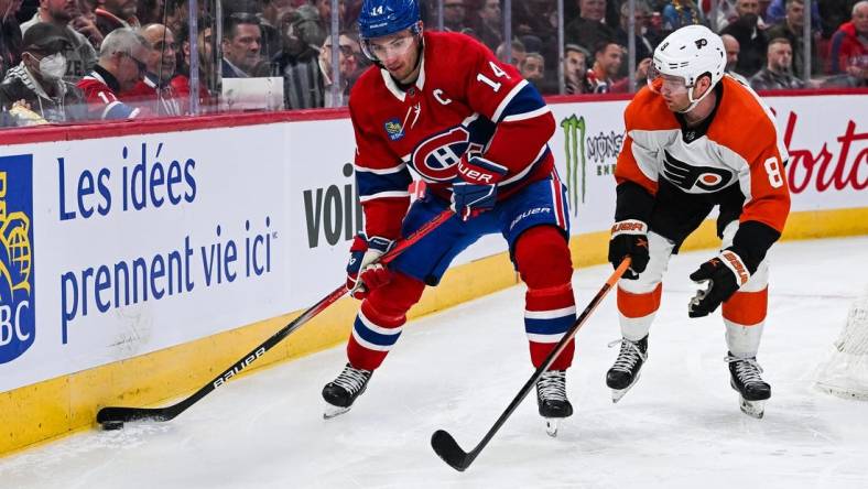 Mar 28, 2024; Montreal, Quebec, CAN; Montreal Canadiens center Nick Suzuki (14) plays the puck against Philadelphia Flyers defenseman Cam York (8) during the second period at Bell Centre. Mandatory Credit: David Kirouac-USA TODAY Sports