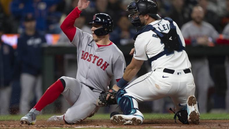 Mar 28, 2024; Seattle, Washington, USA; Boston Red Sox right fielder Tyler O'Neill (17) scores a run after a throw gets past Seattle Mariners catcher Cal Raleigh (29) during the fourth inning at T-Mobile Park. Mandatory Credit: Stephen Brashear-USA TODAY Sports