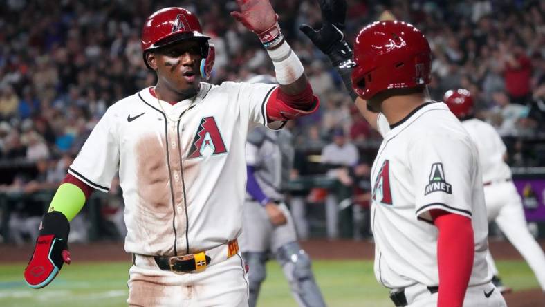 Arizona Diamondbacks Geraldo Perdomo (2) high-fives teammate Gabriel Moreno (14) after scoring a run against the Colorado Rockies on Opening Day at Chase Field.