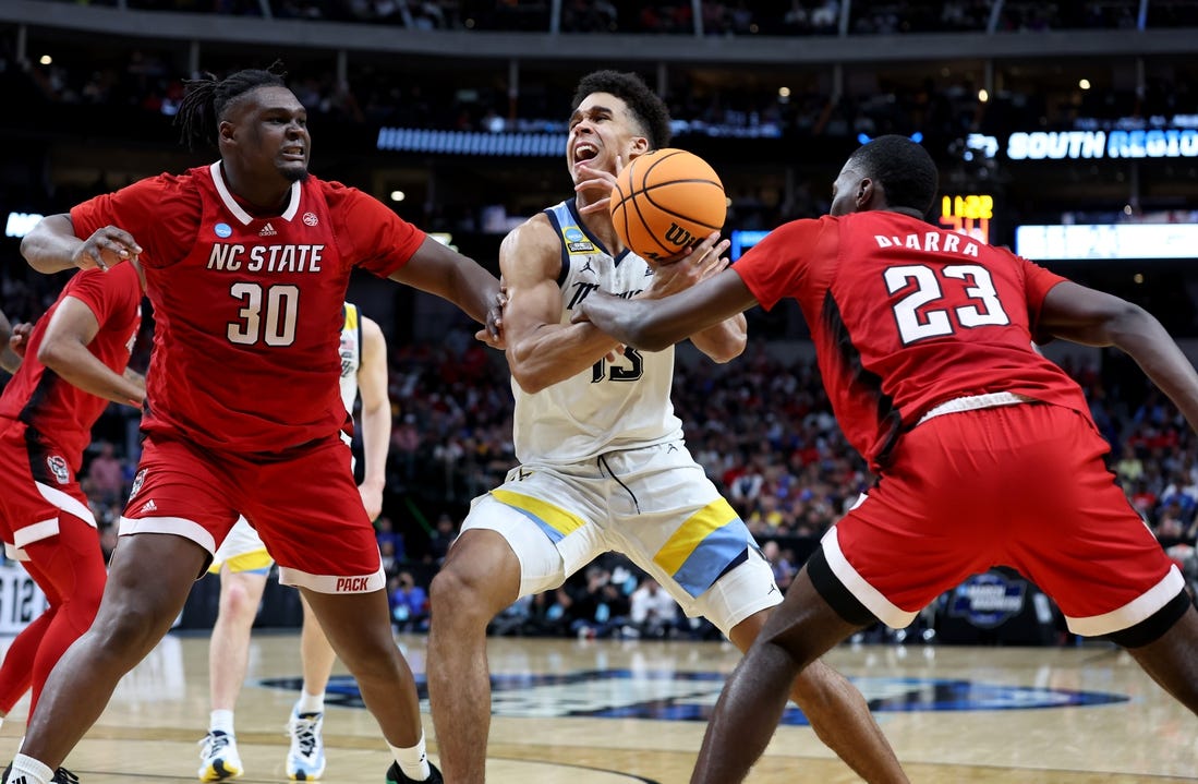 Mar 29, 2024; Dallas, TX, USA; North Carolina State Wolfpack forward Mohamed Diarra (23) knocks the ball away from Marquette Golden Eagles forward Oso Ighodaro (13) as North Carolina State Wolfpack forward DJ Burns Jr. (30) defends during the second half in the semifinals of the South Regional of the 2024 NCAA Tournament at American Airlines Center. Mandatory Credit: Tim Heitman-USA TODAY Sports