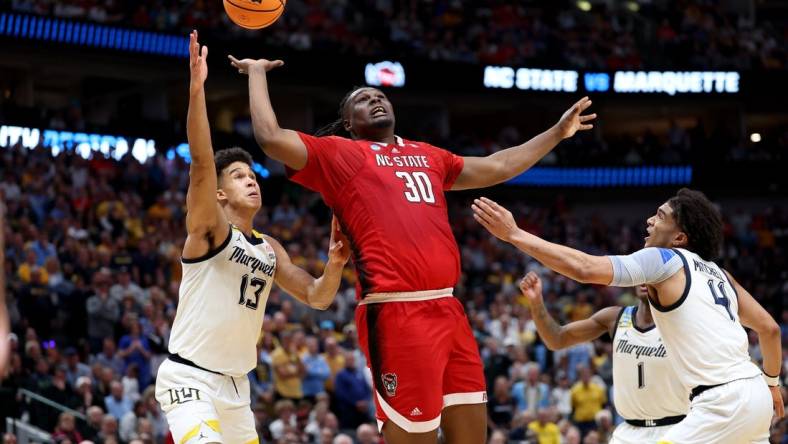 Mar 29, 2024; Dallas, TX, USA; North Carolina State Wolfpack forward DJ Burns Jr. (30) rebounds against Marquette Golden Eagles forward Oso Ighodaro (13),  guard Kam Jones (1) and guard Stevie Mitchell (4) during the second half in the semifinals of the South Regional of the 2024 NCAA Tournament at American Airlines Center. Mandatory Credit: Kevin Jairaj-USA TODAY Sports