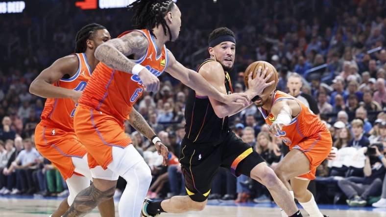 Mar 29, 2024; Oklahoma City, Oklahoma, USA; Phoenix Suns guard Devin Booker (1) drives to the basket between Oklahoma City Thunder guard Aaron Wiggins (21) and forward Jaylin Williams (6) during the first half at Paycom Center. Mandatory Credit: Alonzo Adams-USA TODAY Sports