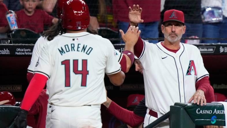 Diamondbacks manager Torey Lovullo high fives Alek Thomas and Gabriel Moreno (14) after the two scored on a Thomas home run against the Rockies during a game at Chase Field.