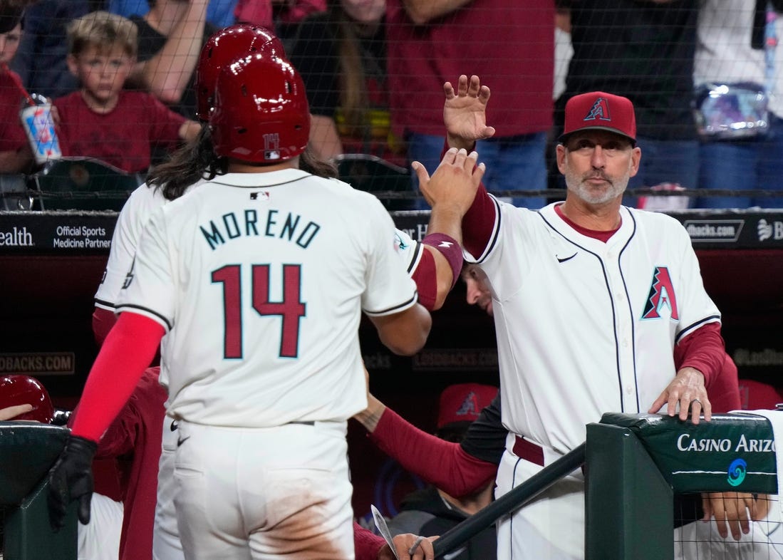 Diamondbacks manager Torey Lovullo high fives Alek Thomas and Gabriel Moreno (14) after the two scored on a Thomas home run against the Rockies during a game at Chase Field.